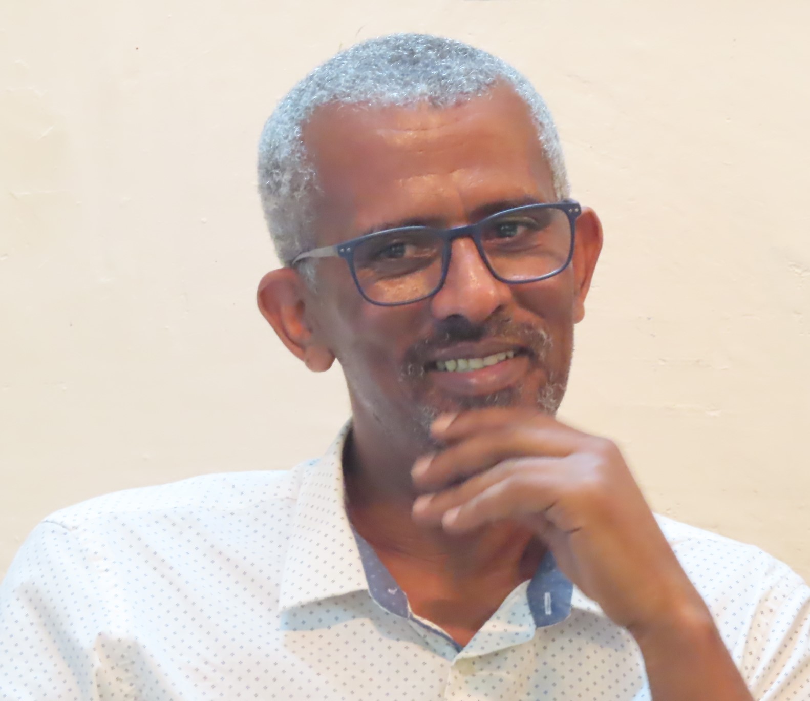 Headshot of smiling gray-haired man wearing eyeglasses